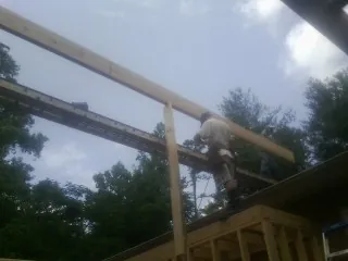 Carpenter setting a ridge beam over a new addition frame — Ice Dam Removal by Roofing Brothers in Azalea