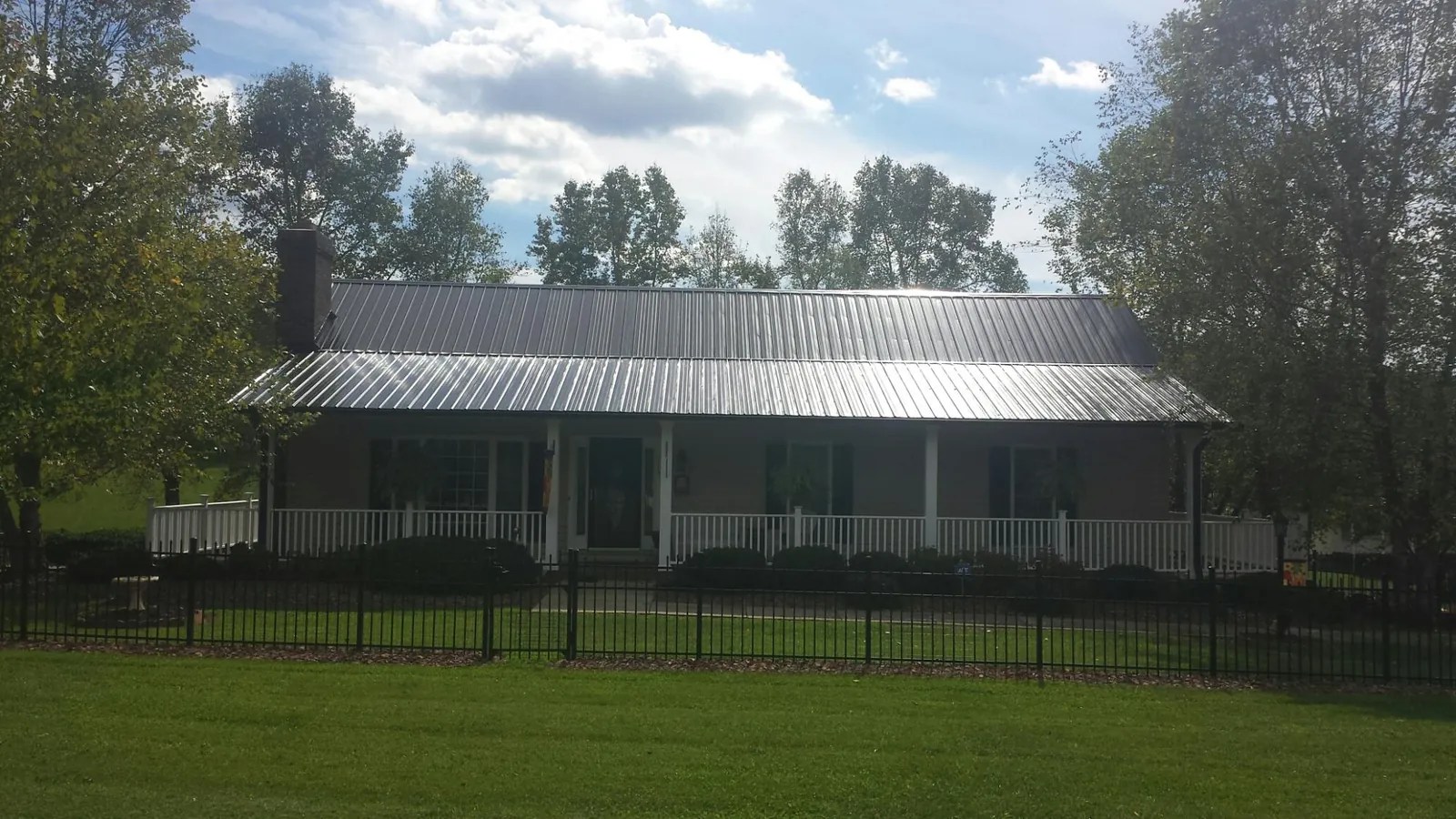 Gray metal roof on a brick ranch with a full width front porch — Gutter Guard Installation work by our crew in Azalea