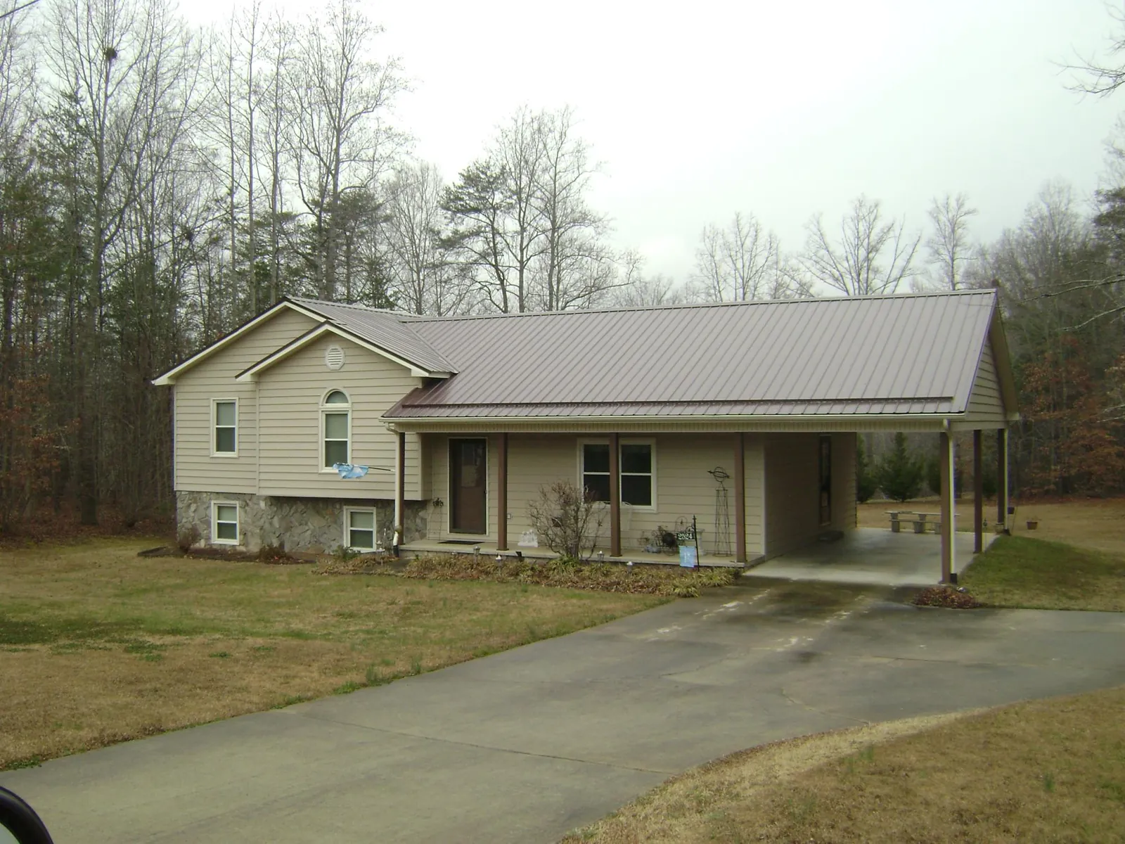 Brown metal roof on a tan split level home with an attached carport in Azalea