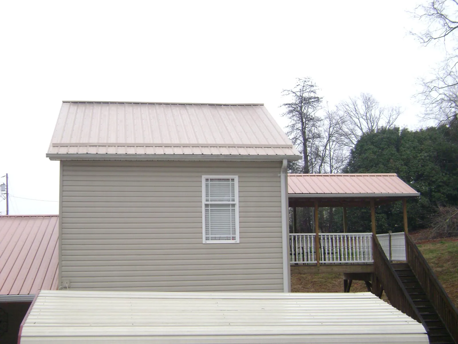 Tan metal roofs on a two story addition and attached porch, from a Roof Replacement job in Azalea